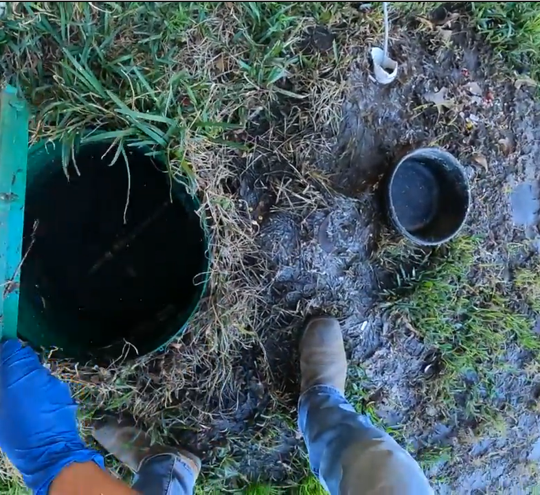 Technician at an open septic tank during a same-day emergency call in Fallbrook